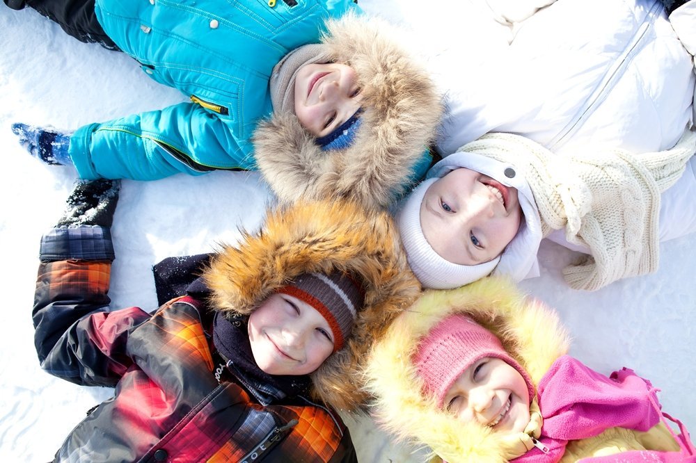 Joyful children lie on their backs on a winter outing