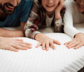 Córka, mama i tata dotykają rękami materaca