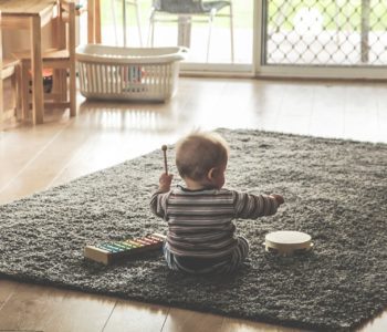 maluszek siedzi na dywanie z bębenkiem