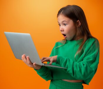 dziewczynka z laptopem zdziwiona mina zielony sweter