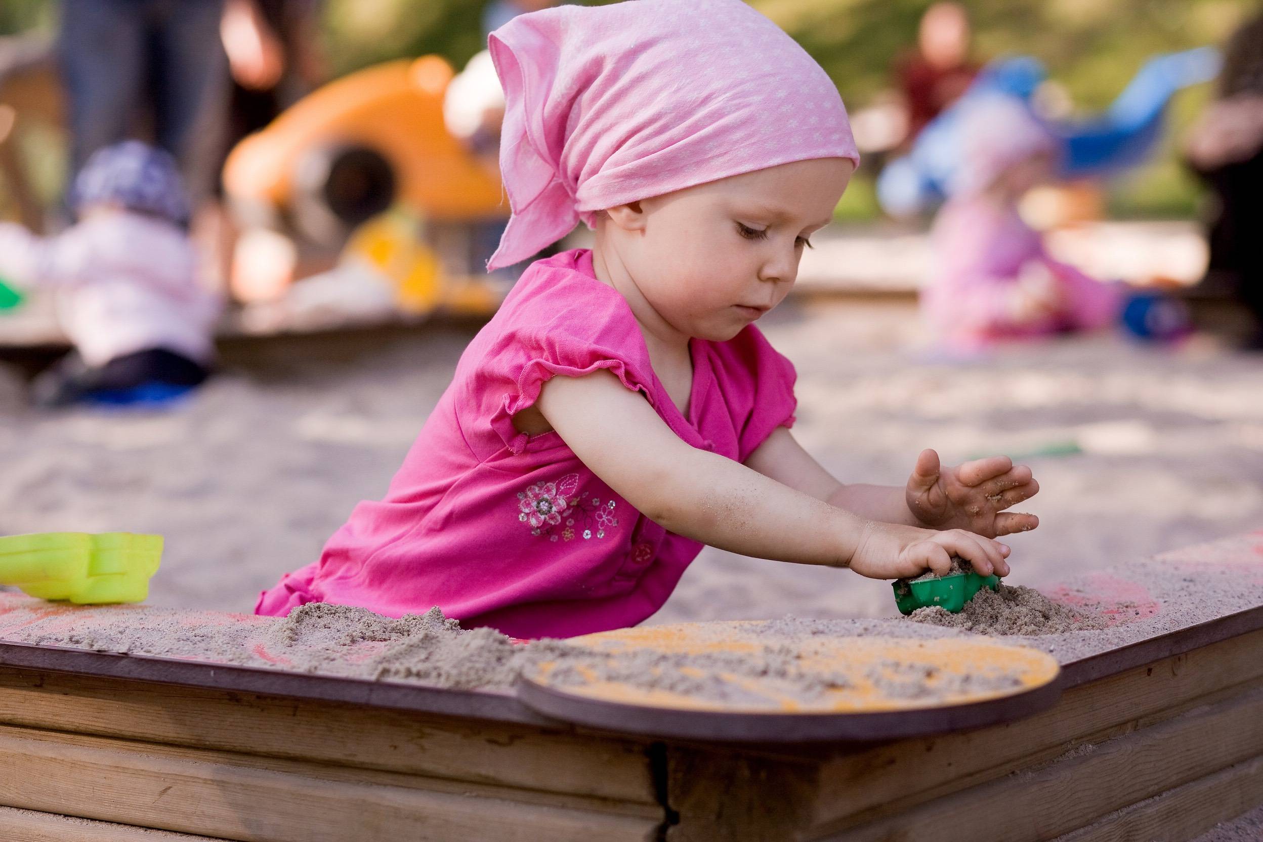 Mała dziewczynka robi babki z piasku w przydomowej piaskownicy