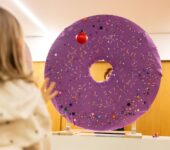 dziewczyna rzuca piłeczką w wielkiego okrągłego pączka