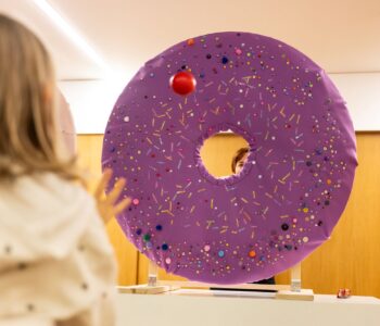 dziewczyna rzuca piłeczką w wielkiego okrągłego pączka