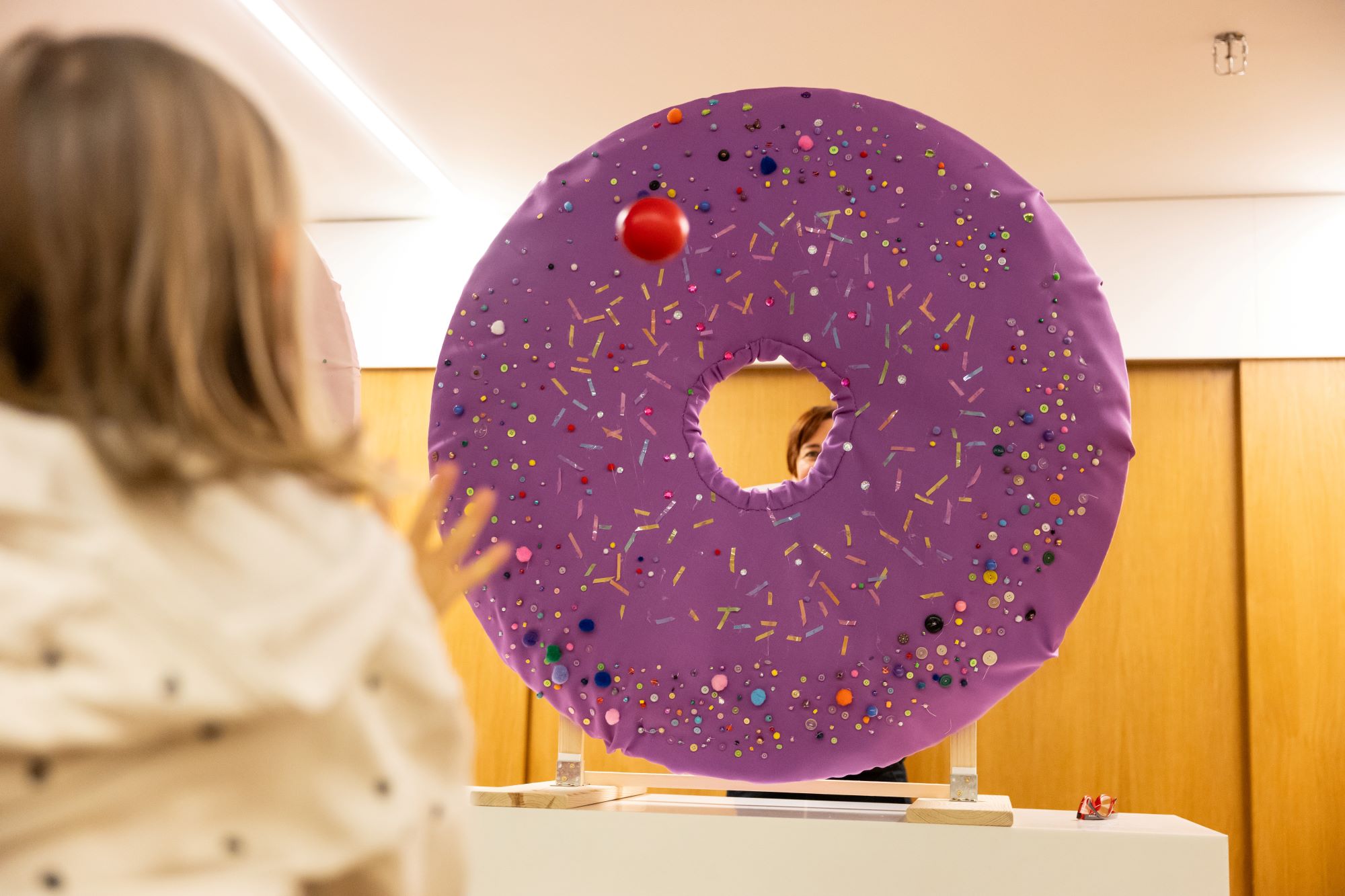 dziewczyna rzuca piłeczką w wielkiego okrągłego pączka