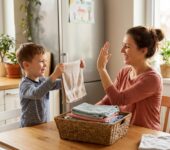 Uśmiechnięta mama i małe dziecko wspólnie wycierają kurze, radosna współpraca przy obowiązkach domowych jako natur...