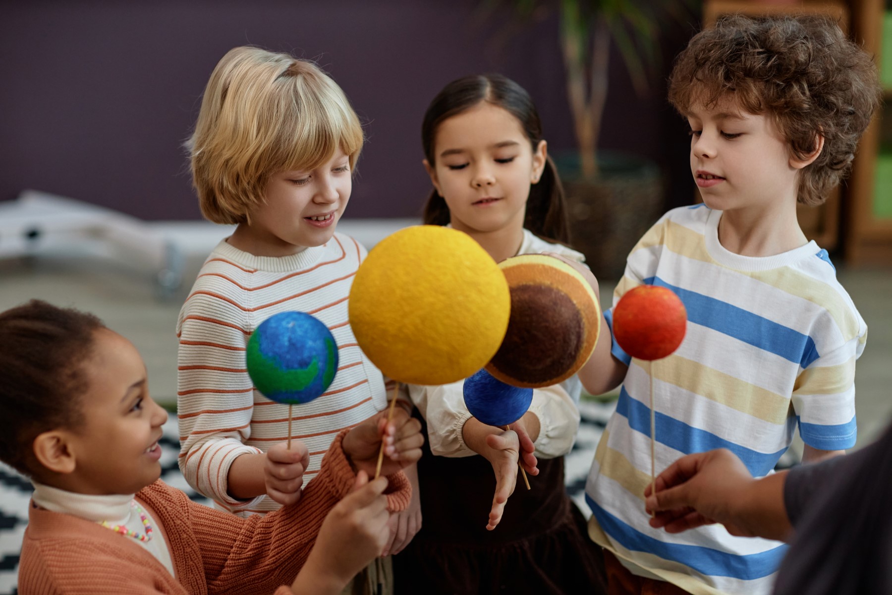 Diverse group of children holding planet models in preschool class