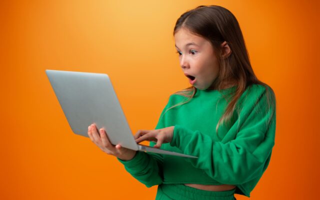 dziewczynka z laptopem zdziwiona mina zielony sweter
